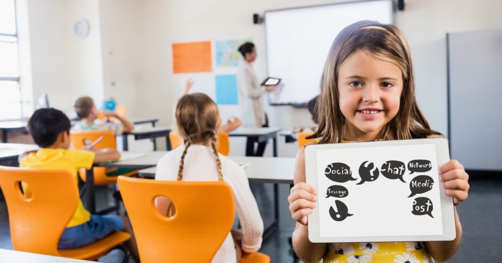 Cute girl showing symbols on tablet computer in classroom