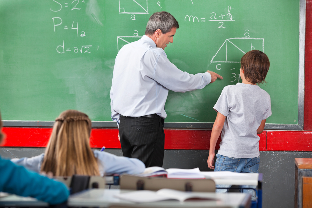 Teacher Assisting Schoolboy While Solving Mathematics